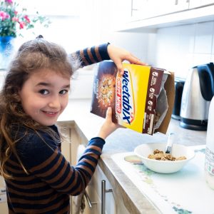 A girl pouring cereal into her bowl