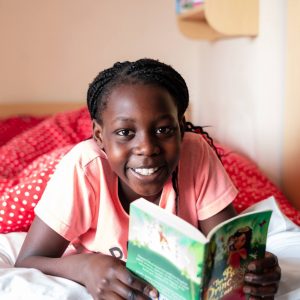 A girl smiling as she reads her book