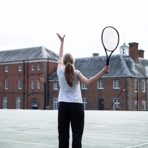 A young school girl playing tennis