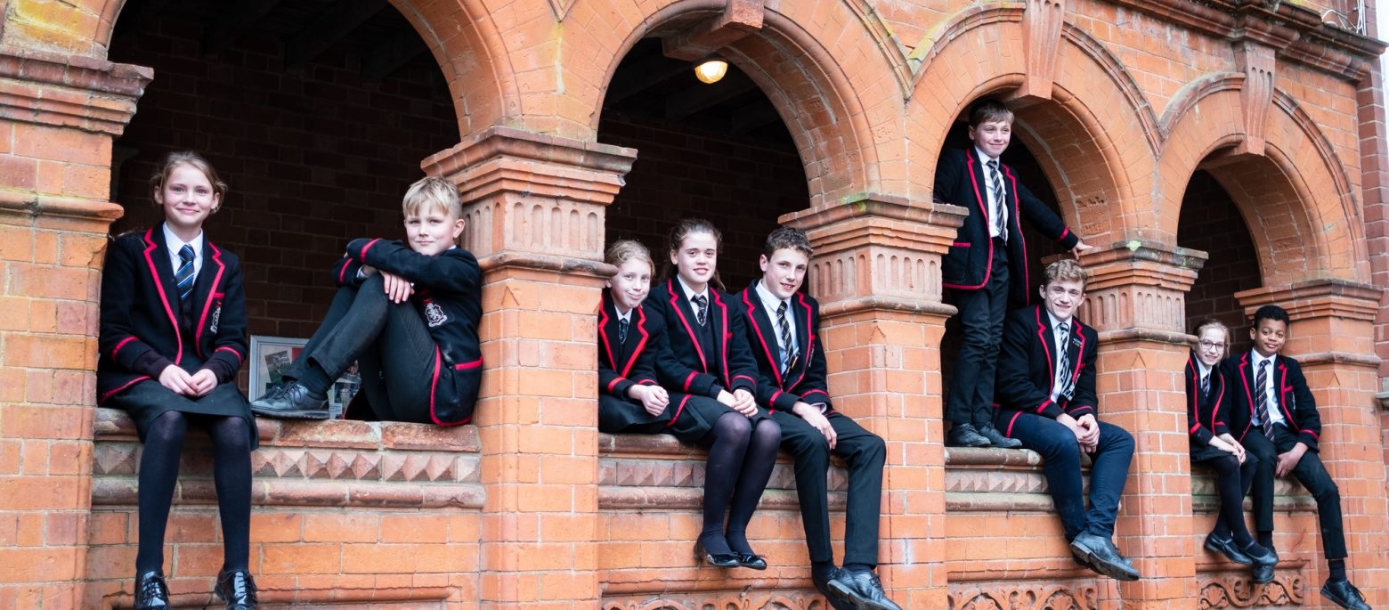 Lucton School children sitting in arches of red brick building