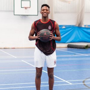 A student smiles as he's holding a basketball