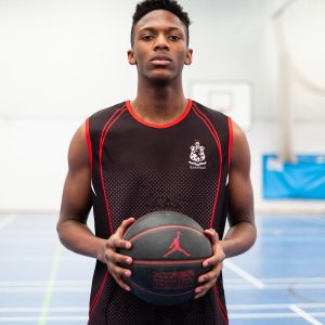 A young school boy holding a basketball