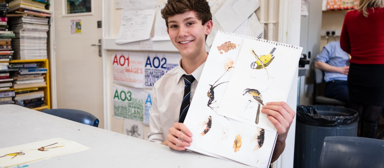 A young school boy showing his many drawings of birds for an art project