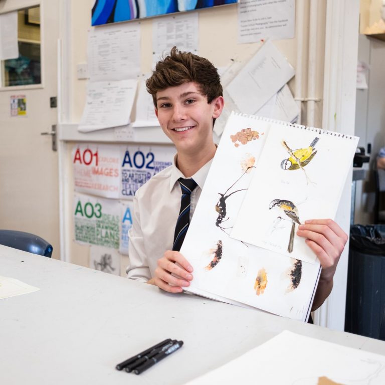 A young school boy showing his many drawings of birds for an art project