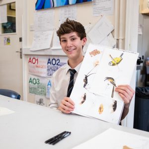 a boy from a middle school in lucton holding his paintings