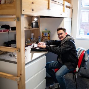 A young school boy working on his school work in his boarding school room