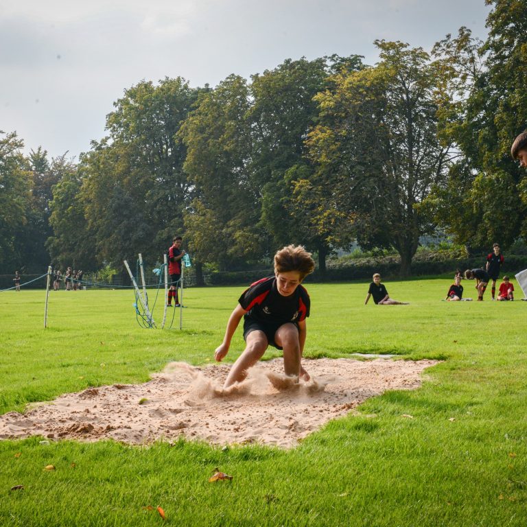 A young boy jumping into the sand