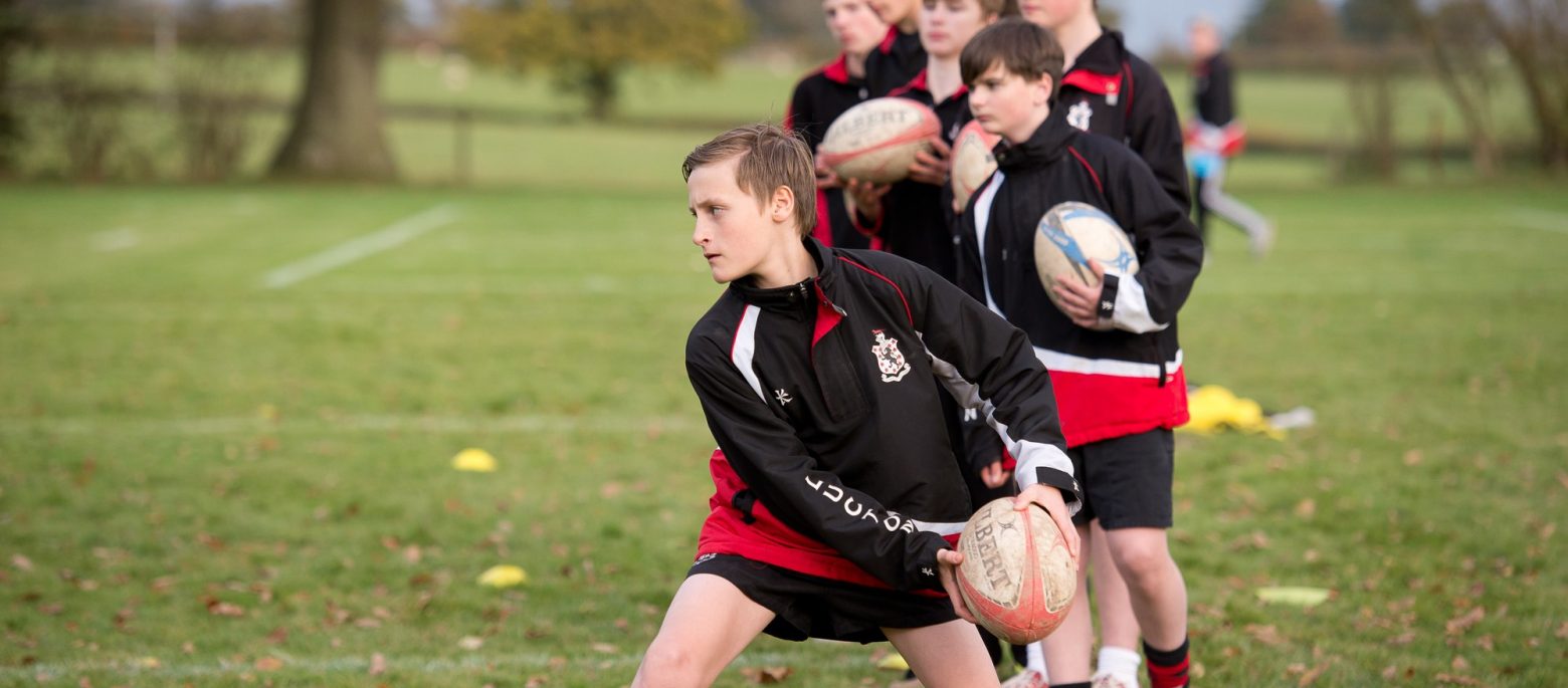 boys standing with rugby balls