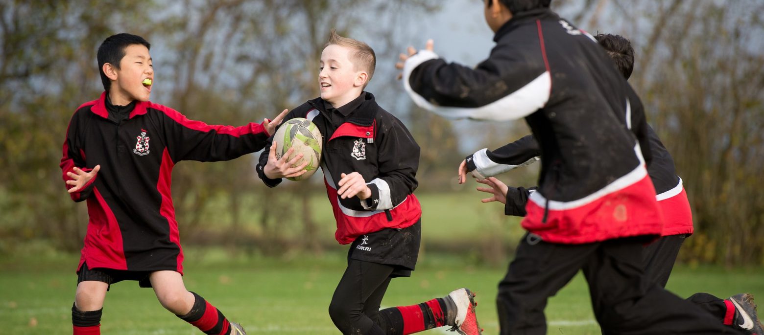 a boy running with a rugby ball