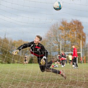 A boy trying to save a goal from entering the net