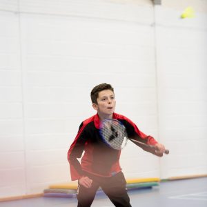 A young schoolboy playing badminton