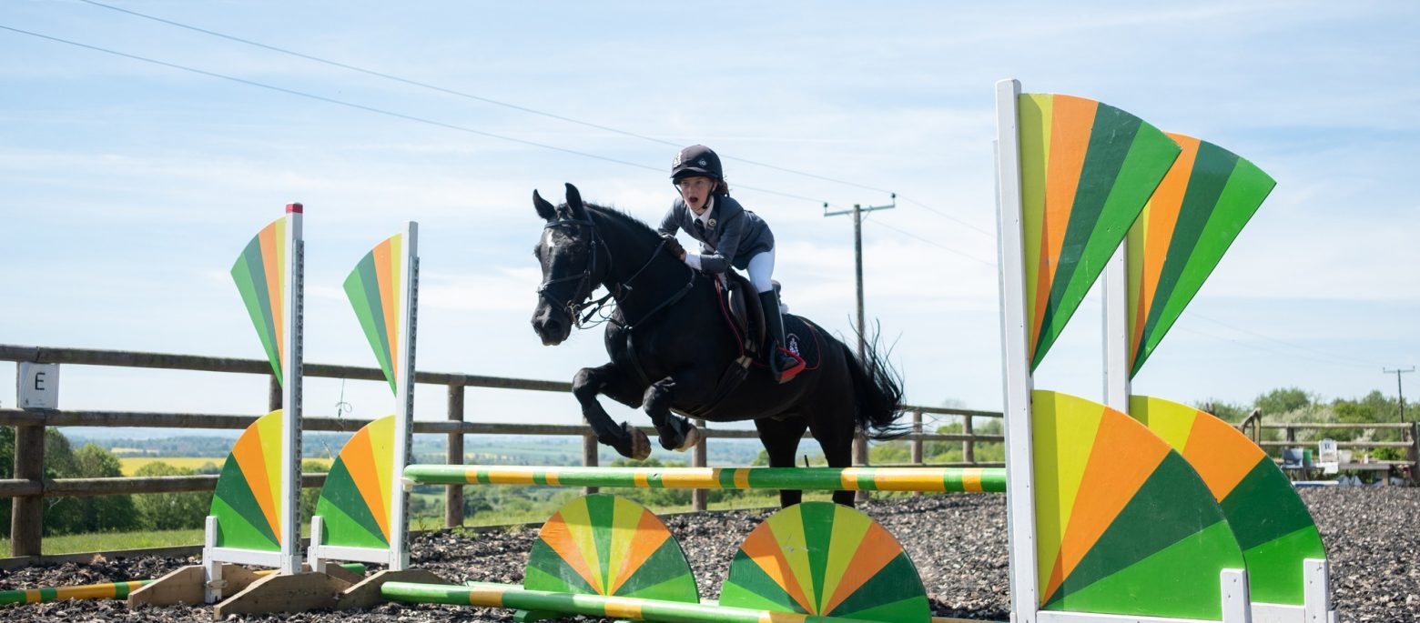 A girl and her horse jumping over a hurdle