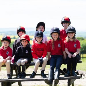 A group of school children smiling as they're sat on the bench