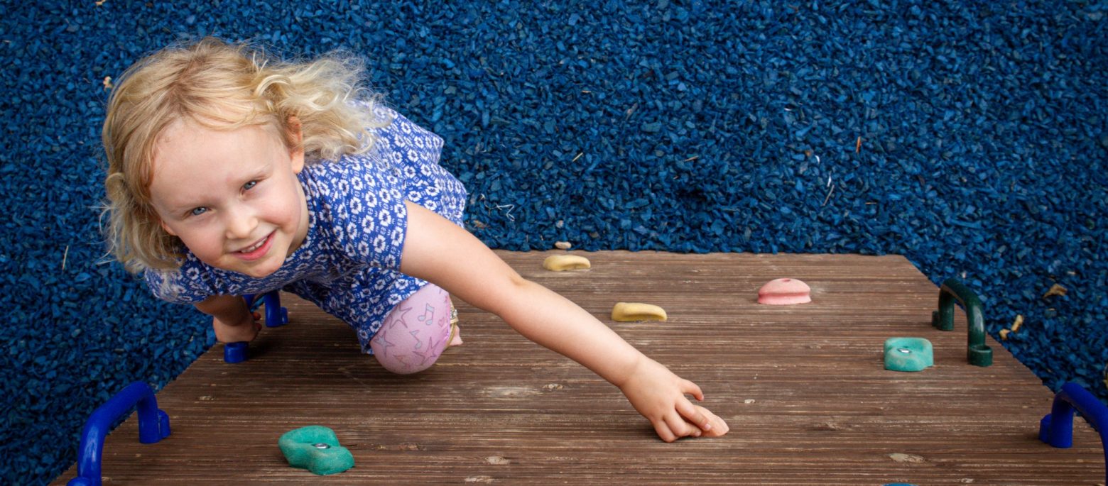 A young girl going up a climbing frame