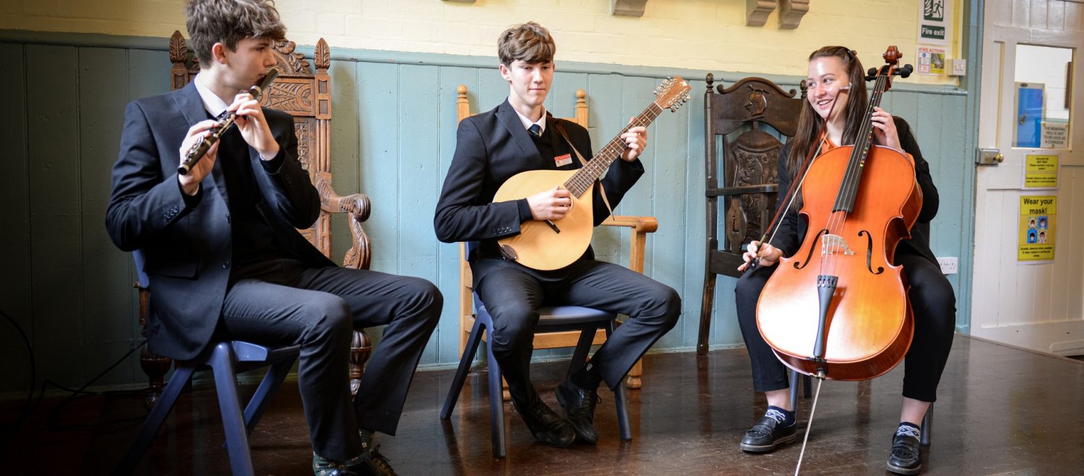 3 school children playing with different instruments - a flute, a lute and a cello