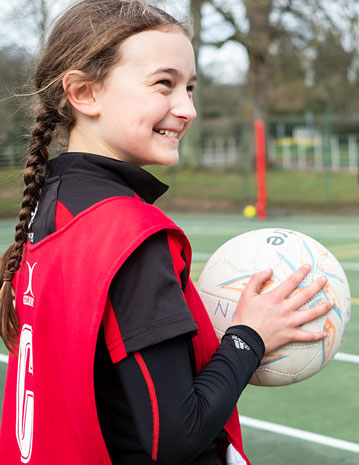 a girl holding a netball and smiling