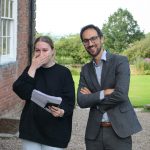 A happy girl smiling at her A Level results with a teacher stood next to her